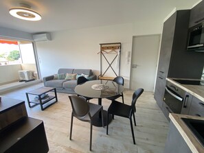 A modern kitchen with a dining area, a sofa, and a TV. - T2 Apartment with South Terrace - Beach Access (Arcachon)