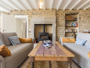 Een gezellige woonkamer met stenen muren, een open haard en een boekenkast.