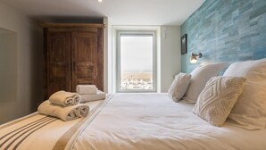 Un dormitori amb llit, armari de fusta, finestra amb vista i paret amb relleu.