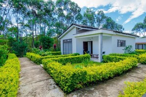 A single-story building with a flat roof, surrounded by well-maintained hedges and trees.