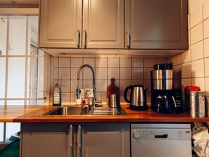 Eine Küche mit Spüle aus Edelstahl, Kaffeemaschine, Wasserkocher und Geschirrspüler.