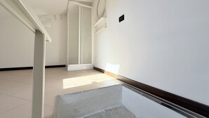 A hallway with a tiled floor, a wooden door, and a white wall with a light switch.
