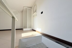 A hallway with a tiled floor, a wooden door, and a white wall with a light switch. - N320 – Numana, a delightful townhouse in the historic center (Numana)