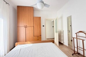 A bedroom with a bed, wooden wardrobe, ceiling fan, radiator, and a mirror. - N320 – Numana, a delightful townhouse in the historic center (Numana)