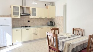 A kitchen with beige cabinets, a gas stove, a microwave, and a dining table with chairs.