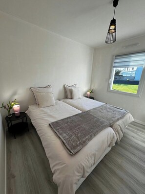 Ein Schlafzimmer mit einem großen Bett, einem Nachttisch mit Lampe, einem Fenster mit Aussicht und einer Hängelampe.