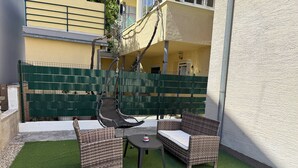 Eine Terrasse mit Korbmöbeln, einem Hängesessel und einem kleinen Tisch.