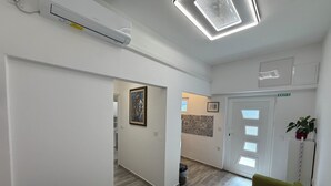 Een modern interieur met een eethoek, een groene bank, een witte deur met een vluchtwijzer en een gang naar een keuken.