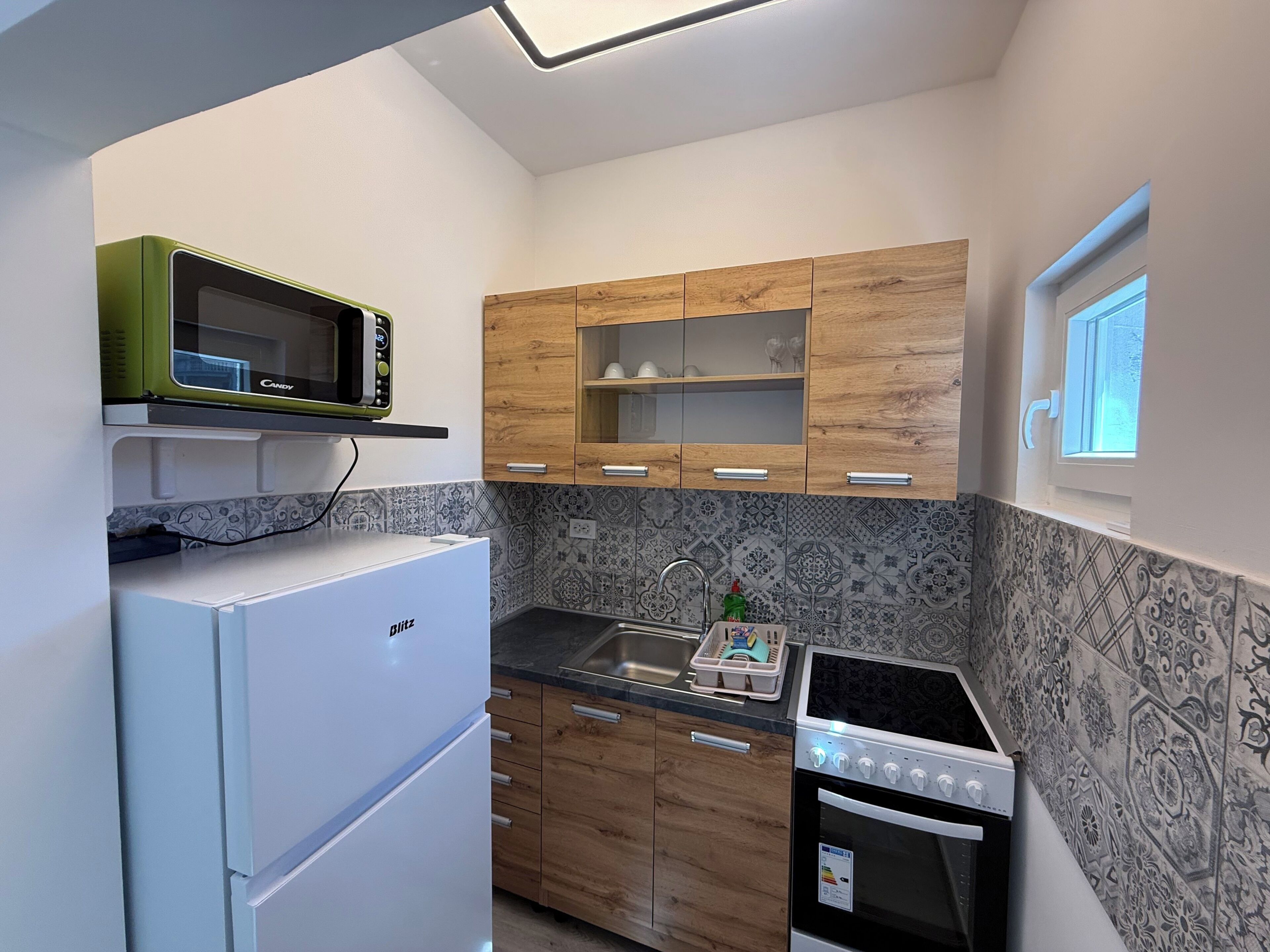 A compact kitchen with a refrigerator, microwave, stove, and wooden cabinets.
