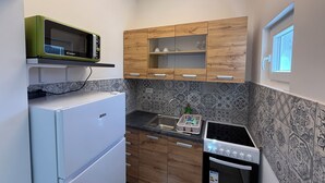 Eine kleine Küche mit Kühlschrank, Mikrowelle, Herd und Holzschränken.