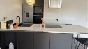 Una cocina moderna con una isla central, iluminación colgante y un horno empotrado.