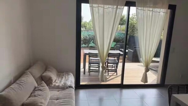 Una habitación con un sofá, una mesa de comedor con sillas y un ventanal corredero que da a un patio exterior.