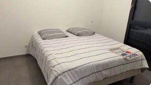 Una cama pequeña y bien hecha con ropa de cama a rayas y dos almohadas.