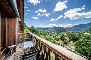 A wooden balcony with a table and chairs, overlooking a mountainous landscape. - Renovated Farmhouse in Mieussy with Mountain View, Private Terrace and Wi-Fi (Mieussy)
