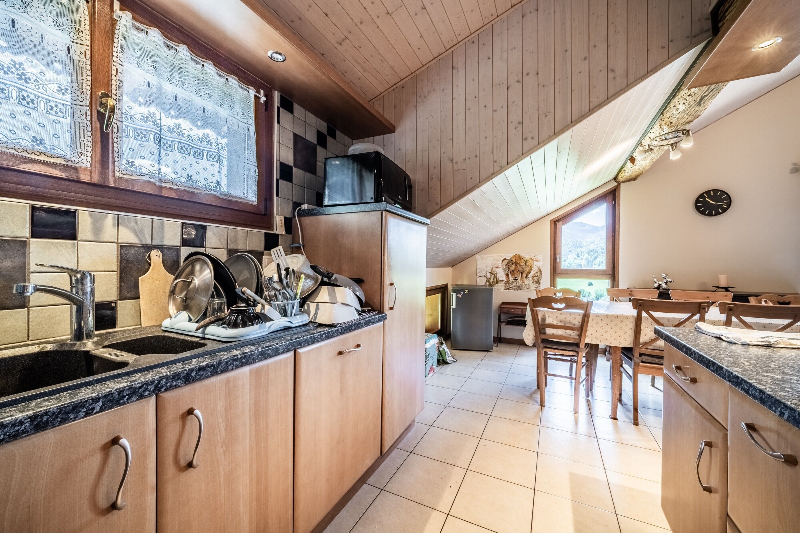 Une cuisine avec des meubles de rangement en bois, un évier et un coin repas comprenant une table et des chaises.