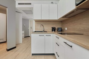 A modern kitchen with white cabinets, a wooden countertop, and a built-in sink. - Stylish Apartment with Air Conditioning | Next to C.H. Wroclavia (Wrocław)