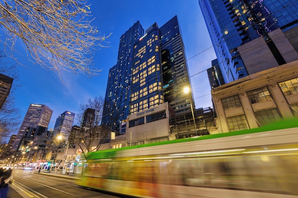 A cityscape with modern high-rise buildings, a tram in motion, and a clear sky. - Brady Hotels Elizabeth Street (Melbourne)