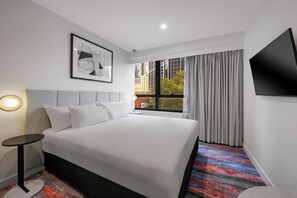 A hotel room with a bed, a flat-screen TV, a framed picture on the wall, and a window with curtains. - Brady Hotel Elizabeth Street (Melbourne)