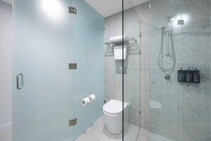 Een moderne badkamer met een douchecabine van glas, een toilet en een handdoekhouder.