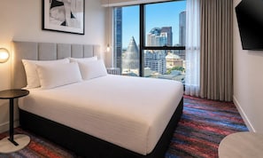 A hotel room with a large bed, a round side table, a city view through the window, and a framed picture on the wall. - Brady Hotel Elizabeth Street (Melbourne)
