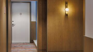 A hotel corridor with a wooden door, a light fixture, and a striped carpet.