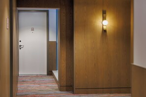 A hotel corridor with a wooden door, a light fixture, and a striped carpet. - Brady Hotels Elizabeth Street (Melbourne)