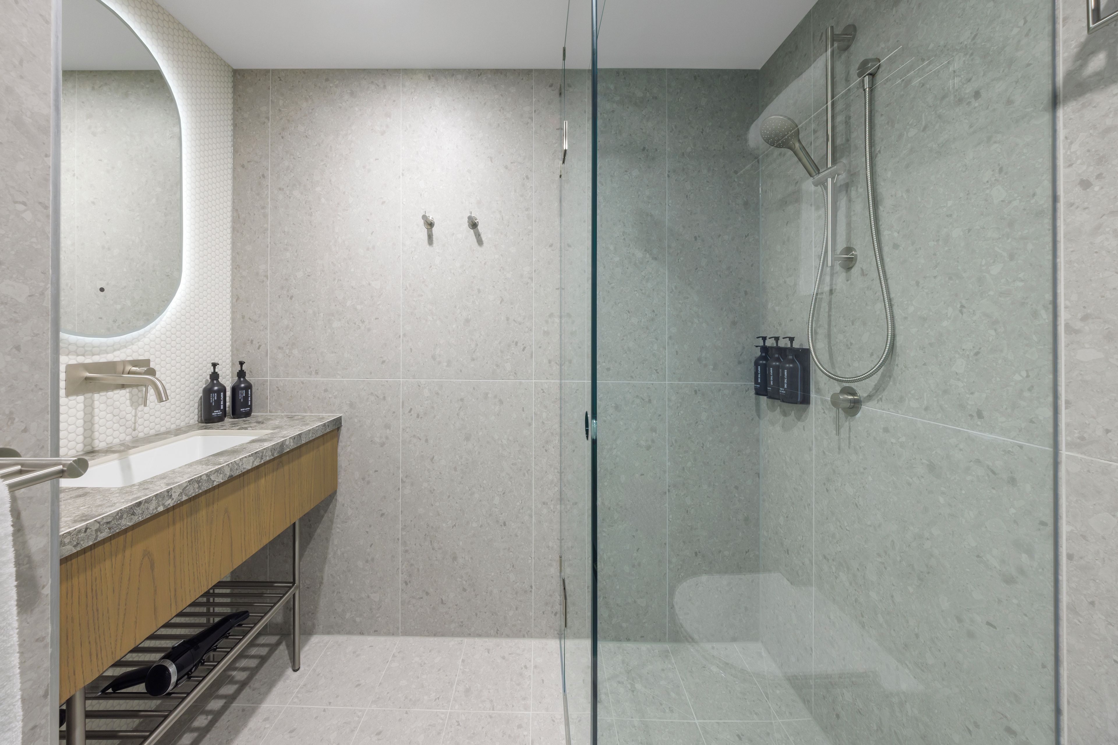 Une salle de bain moderne avec une douche à parois de verre, un meuble-lavabo en bois et un grand miroir.