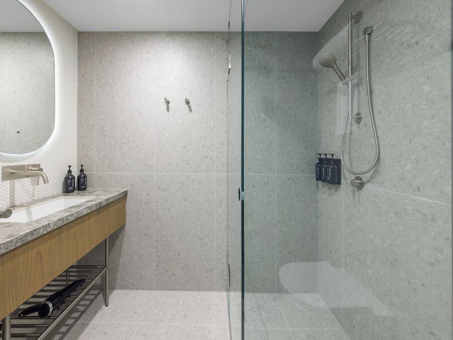 Un baño moderno con cabina de ducha de vidrio, tocador de madera y un espejo grande.