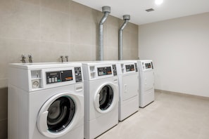 A row of commercial washers in a clean, tiled room with a simple layout. - Brady Hotels Elizabeth Street (Melbourne)
