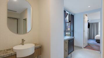 Un bagno moderno con uno specchio rotondo, un lavandino e una doccia.