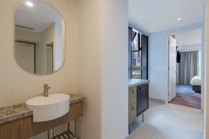 A modern bathroom with a round mirror, a sink, and a shower area.