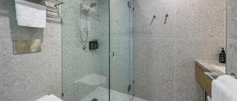 Un baño moderno con ducha de vidrio, inodoro y lavamanos.