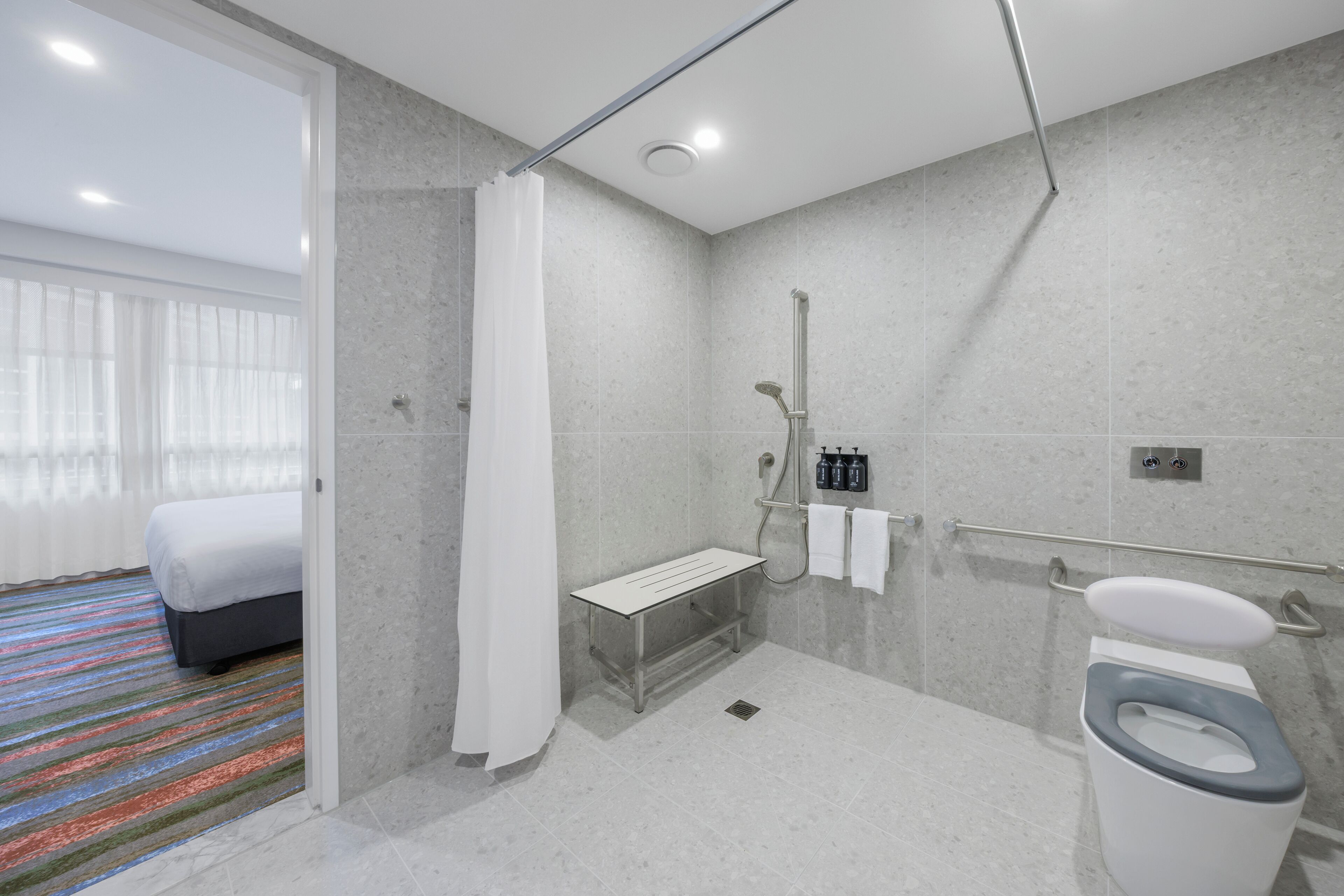 Un baño moderno con ducha, inodoro y un banco.