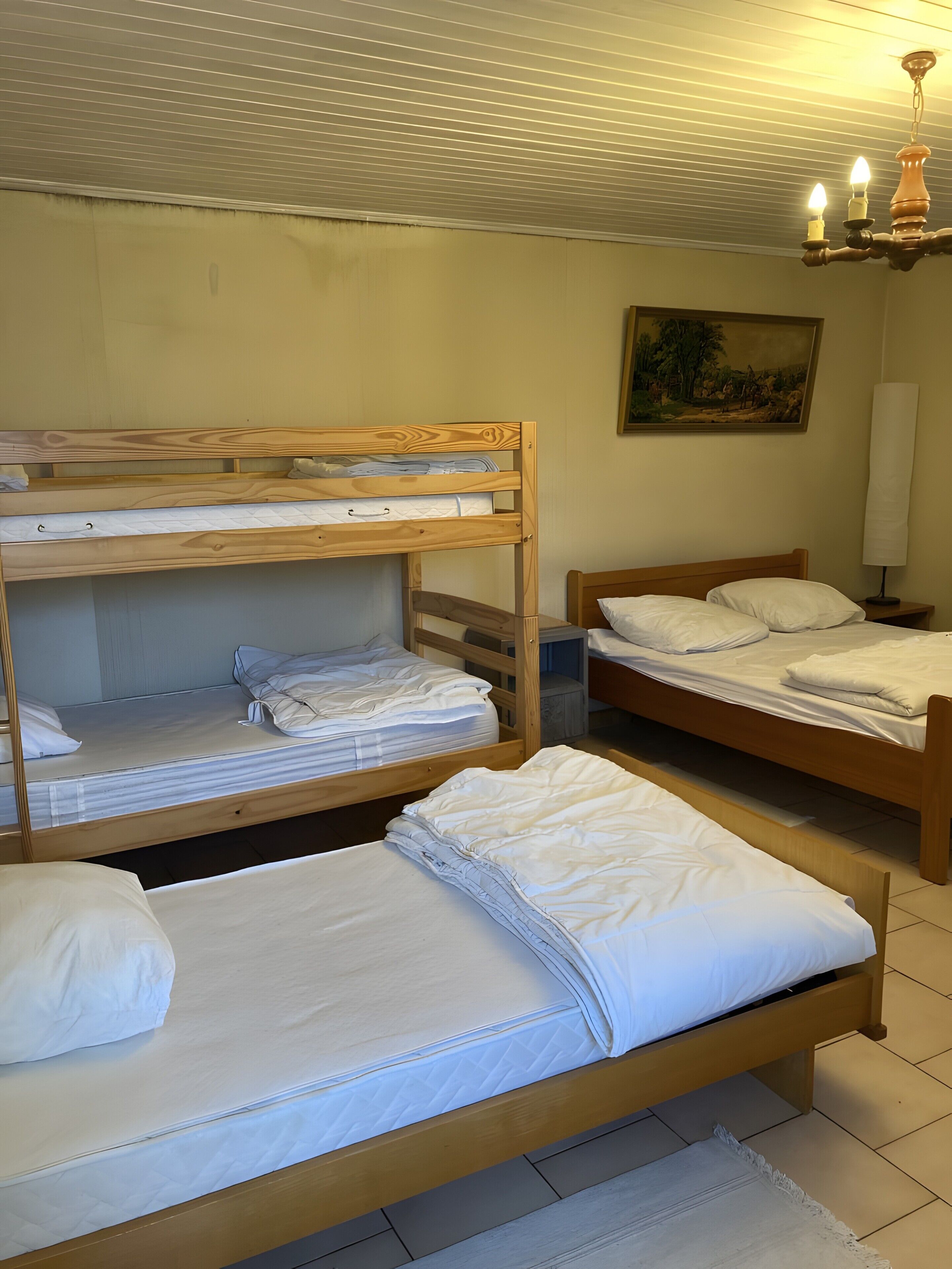 A room with bunk beds, a painting on the wall, and a lamp.