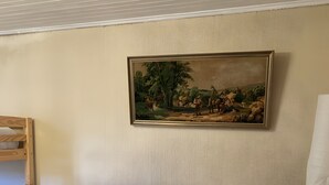 A neatly made bed with white linens, a wooden headboard, and a painting of a rural scene on the wall. - Holiday Home “Gîte Des 4 Lacs Bis” with Mountain View, Private Terrace & Wi-Fi (Vertamboz)