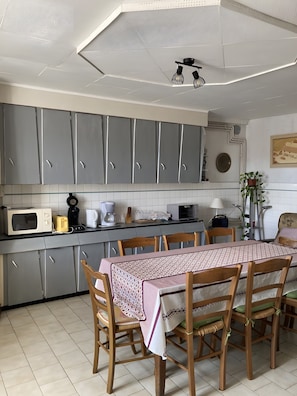 A kitchen with grey cabinets, a dining table with chairs, a microwave, a toaster, and a coffee maker. - Holiday Home “Gîte Des 4 Lacs Bis” with Mountain View, Private Terrace & Wi-Fi (Vertamboz)