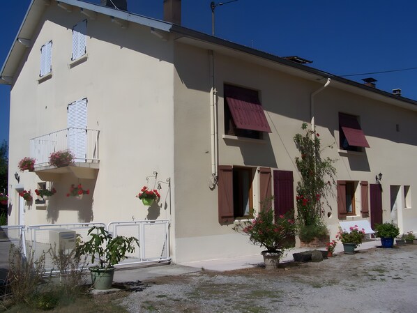 Un edificio a due piani con balconi, piante in vaso e un ingresso con cancello.