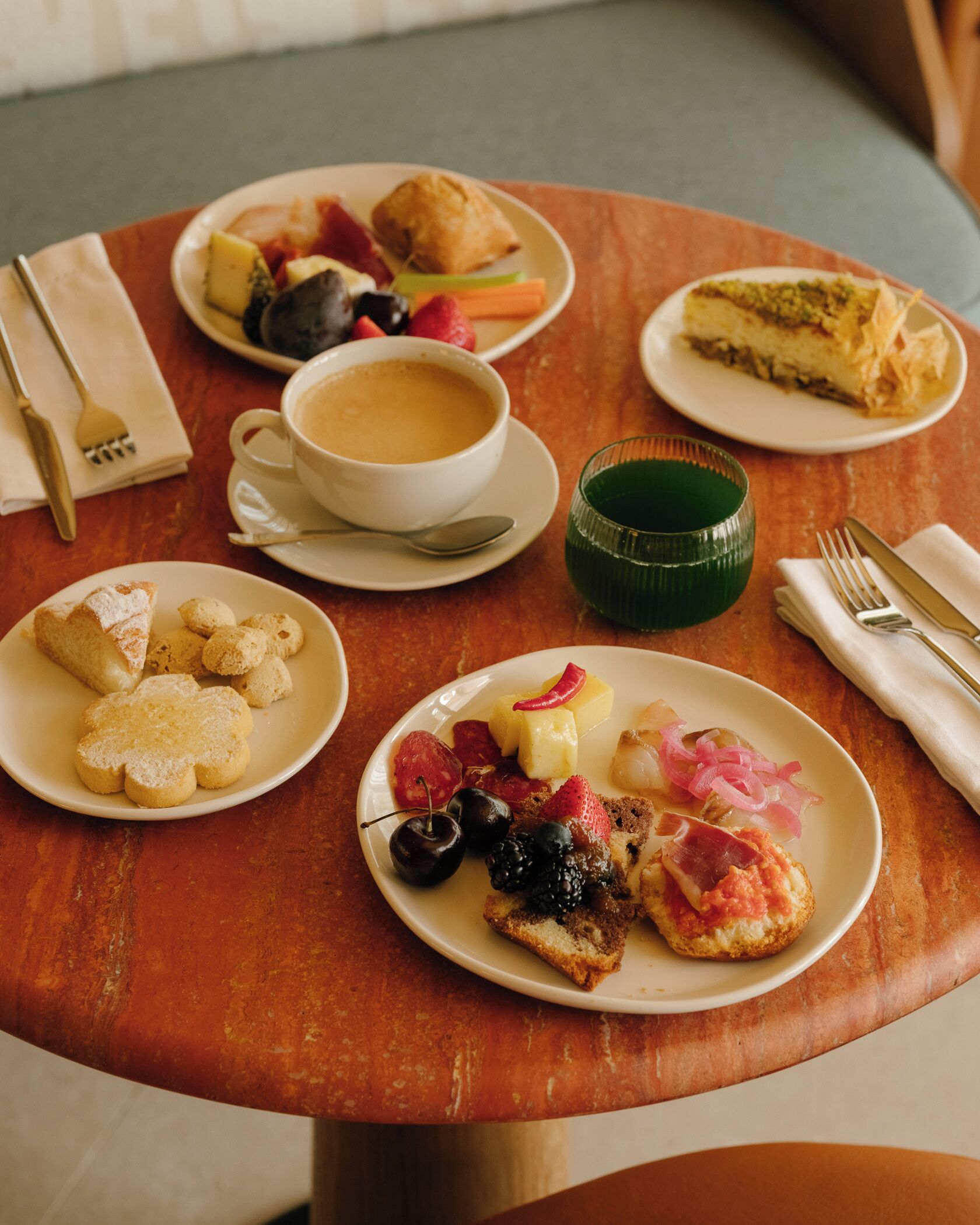 Une table garnie de divers aliments pour le petit-déjeuner, notamment des viennoiseries, des fruits et une tasse de café.