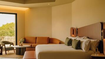 A hotel room with a large bed, a sofa, a small table, and a chair.