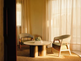 Um quarto com uma mesa redonda, duas cadeiras e uma pequena planta.