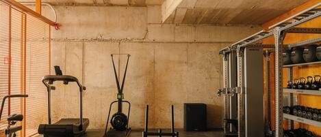 A gym with exercise equipment, a weight rack, and a concrete ceiling.