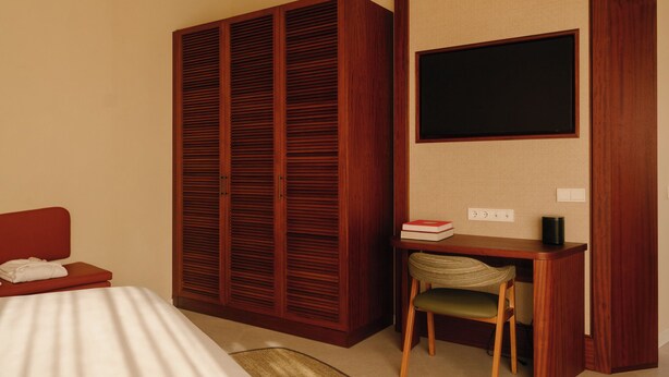 A hotel room with a bed, a desk with a chair, a wardrobe, and a television on the wall. - RIVELIAN Grand Menorca (Ciutadella de Menorca)