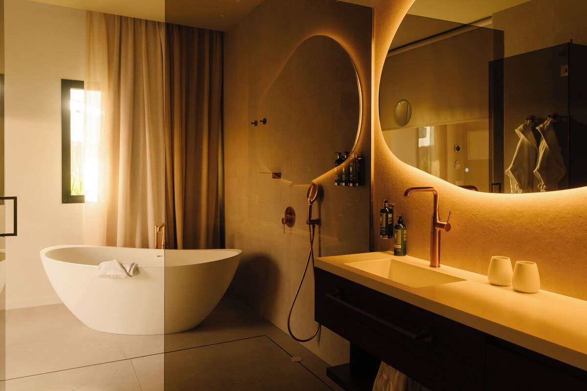 A modern bathroom with a freestanding bathtub, a large mirror, and a vanity with two sinks.