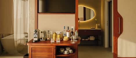 Habitación de hotel con una mesita de madera, televisor de pantalla plana, espejo y minibar.
