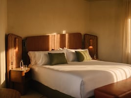 A hotel room with a large bed, wooden headboard, two bedside tables, and a nightstand.