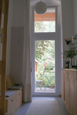 A hallway leading to a door with a view of a garden and a table outside. - DAS STUDIO: Tiny apartment with garden oasis in the middle of Berlin (Berlin)