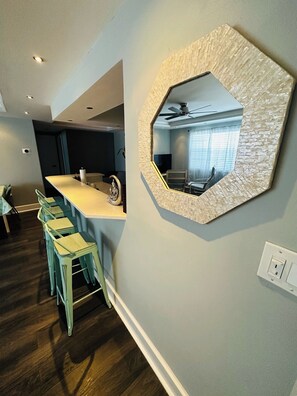 Eine moderne Küche mit Bar, Holzbarhocker und einem großen sechseckigen Spiegel an der Wand.