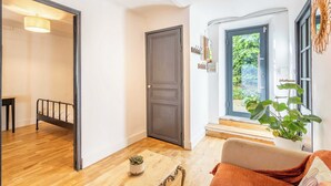 Una habitación con cama, una mesita, una planta en maceta y vistas al verdor exterior.