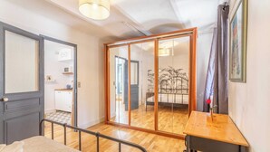 Un dormitorio con cama, una mesa de madera, un espejo, una puerta corredera y vistas a la cocina y al baño.