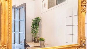Un baño con un espejo grande, una planta en maceta y una puerta.